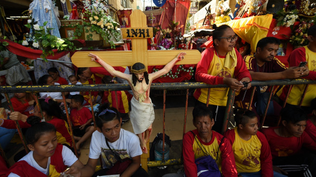 Sejumlah umat katolik Filipina menunggu prosesi keagamaan Balck Nazarane di dekat gereja Quiapo, Manila, Filipina, (9/1).   (Foto: AFP/TED ALJIBE)