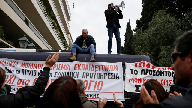 Para guru sekolah Yunani meneriakkan slogan-slogan dari atas bus polisi saat demonstrasi di depan gedung parlemen, Athena, Yunani (11/1). (Foto: Reuters/Costas Baltas)