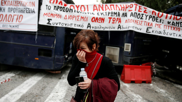 Seorang pemrotes menutupi wajahnya untuk melindungi dari gas air mata ketika para guru sekolah Yunani mulai bentrok dengan polisi. (Foto: Reuters/Costas Baltas)
