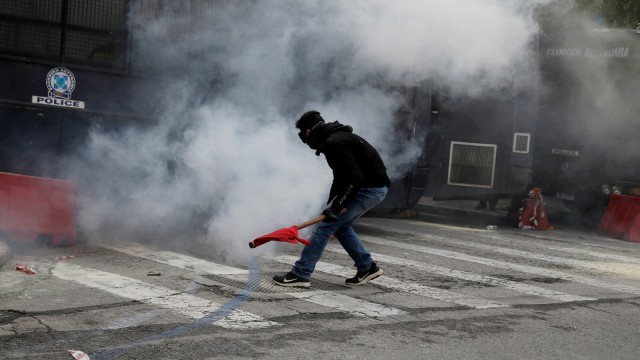 Seorang pengunjuk rasa berlari di tengah asap gas air mata ketika para guru sekolah Yunani bentrok dengan polisi, Athena (11/1). (Foto: Reuters/Costas Baltas)