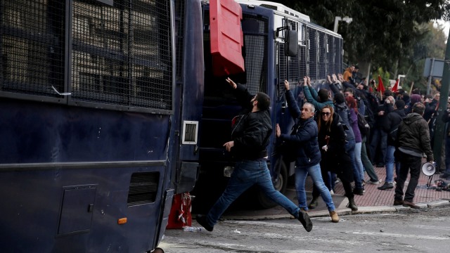 Para pengunjuk rasa mendorong bus polisi ketika para guru sekolah Yunani bentrok dengan polisi anti huru hara selama demonstrasi. (Foto: Reuters/Costas Baltas)