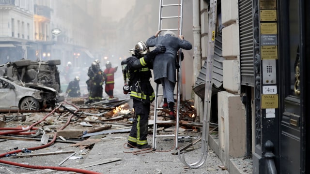 Seorang wanita dievakuasi oleh petugas pemadam kebakaran setelah ledakan sebuah toko roti di sudut jalan Saint-Cecile dan Rue de Trevise di pusat kota Paris (12/1). (Foto: AFP/Thomas SAMSON)