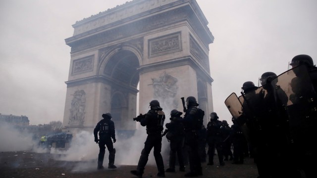 Polisi anti berjaga-jaga berjaga dan melemparkan gas air mata kepada para demonstran "Rompi Kuning", Paris, Prancis Sabtu (12/1/2019). (Foto: REUTERS/Christian Hartmann)