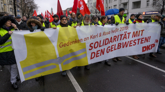 Para demonstran membawa banner yang bertuliskan "Mengingat Karl dan Rosa" di 100 tahun kematiannya di Berlin, Jerman, Minggu (13/1/2019). (Foto: AFP/JOHN MACDOUGALL )