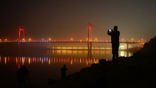 Seorang pria mengambil gambar Jembatan Yamuna Baru, yang dibangun di atas Sungai Yamuna, India. (Foto: AFP/SANJAY KANOJIA)