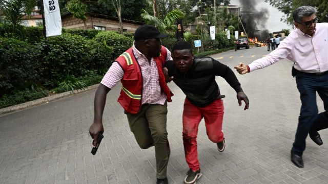 Seorang warga dievakuasi dari tempat ledakan di sebuah hotel di  Westlands, Nairobi, Kenya (15/1/19).  (Foto: AFP/SIMON MAINA)