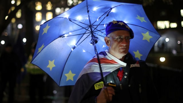 Seorang demonstran Pro-Uni Eropa berdiri di bawah payung bendera Uni Eropa, London, Inggris. (Foto: AFP/DANIEL LEAL-OLIVAS)