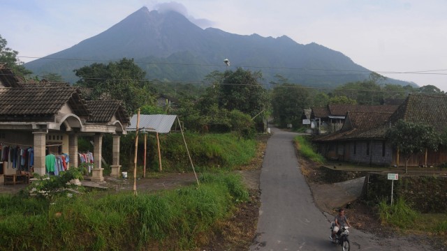 Warga melintas di jalan desa dengan berlatar belakang Gunung Merapi terlihat dari Balerante, Kemalang, Klaten, Jawa Tengah, Senin (14/1/2019).  (Foto: ANTARA FOTO/Aloysius Jarot Nugroho)