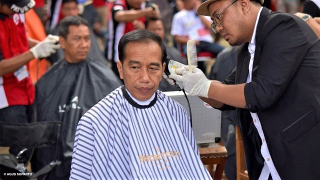 Presiden Joko Widodo saat dipangkas rambutnya oleh Herman, pemuda asal Garut. (Foto: Presidential Palace/Agus Suparto)