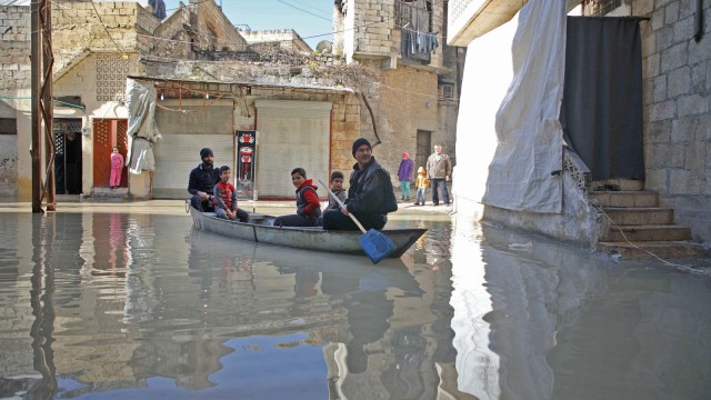 Seorang pria mendayung sebuah perahu kecil mengangkut anak-anak di kota Darkush. (Foto: AFP/Aaref WATAD)