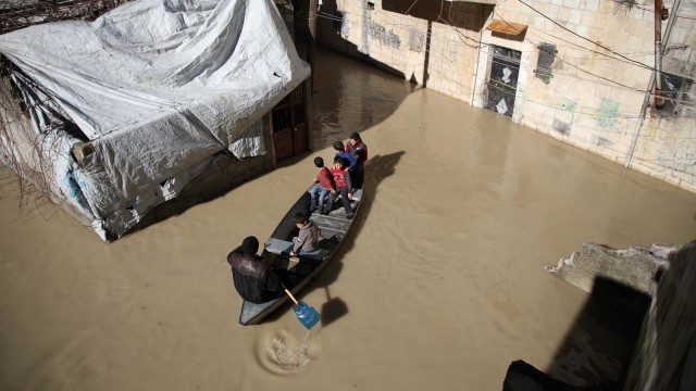Anak-anak menikmati perjalanan dengan perahu kecil di sepanjang jalan yang banjir di kota Darkush. (Foto: AFP/Aaref WATAD)