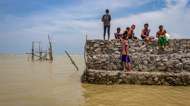 Sejumlah anak bermain di atas tanggul penahan gelombang air laut. Foto: ANTARA FOTO/Aji Styawan