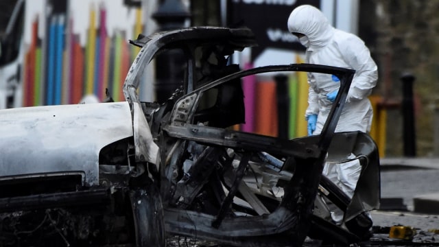 Petugas forensik melijat mobil yang hangus terbakar akibat ledakan bom mobil di Londonderry, Irlandia, (20/1).  (Foto: REUTERS / Clodagh Kilcoyne)