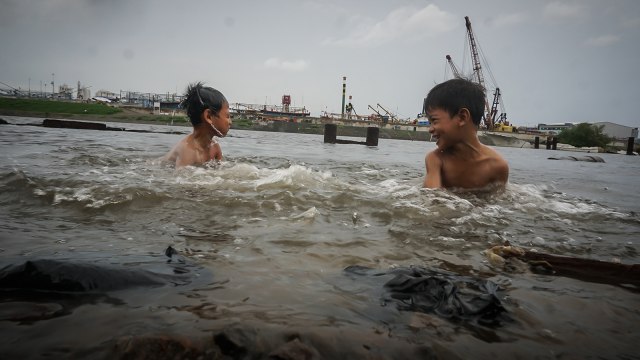Dua orang anak berenang di kawasan Penjaringan. (Foto: Jamal Ramadhan/kumparan)