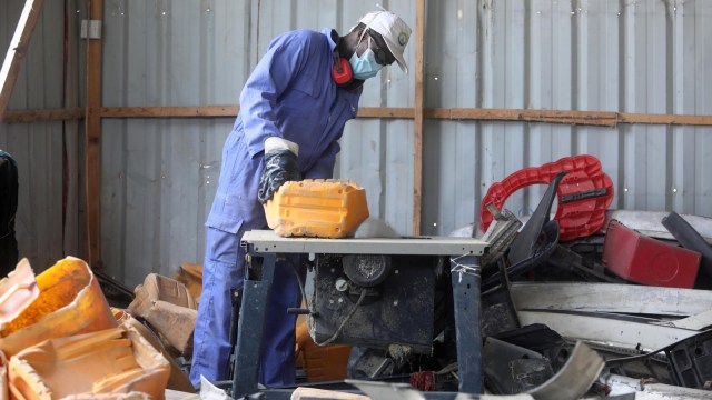 Seorang pria memotong sampah plastik sebelum didaur ulangn menjadi genteng di pabrik daur ulang Envirogreen di Mogadishu, Somalia. (Foto: REUTERS/Feisal Omar)