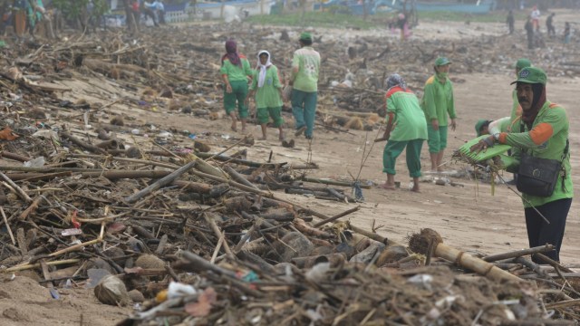 Sejumlah petugas membersihkan tumpukan sampah yang berserakan di kawasan Pantai Kuta, Badung, Bali, Rabu (23/1).  (Foto: ANTARA FOTO/Fikri Yusuf)