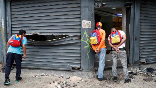 Sejumlah warga melihat hancurnya swalayan yang dijarah di Caracas, Venezuela (24/1/2019). (Foto: REUTERS/Carlos Garcia Rawlins)