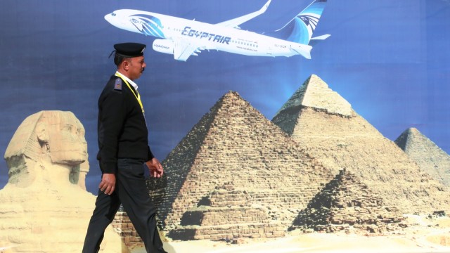 Seorang petugas polisi berjalan di depan sebuah poster sebuah pesawat Mesir di Bandara Internasional Sphinx yang baru di Kairo barat, Mesir  (Foto: REUTERS/Mohamed Abd El Ghany)