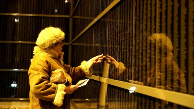 Seorang perempuan berdiri di depan dinding yang berisikan nama-nama korban Holocaust, dalam memperingati Internasional Holocaust, di Pusat Budapest, Hungaria (27/1/2019). (Foto: REUTERS/Bernadett Szabo)