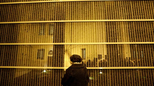 Seorang perempuan berdiri di depan dinding yang berisikan nama-nama korban Holocaust, dalam memperingati Internasional Holocaust, di Pusat Budapest, Hungaria (27/1/2019). (Foto: REUTERS/Bernadett Szabo)
