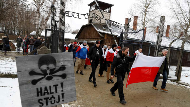 Sejumlah aktivis berjalan melewati kamp konsentrasi bekas jerman yang bernama "Arbeit Macht Frei", dalam memperingati hari holocaust internasional di Oswiecim, Polandia (27/1/2019). (Foto: REUTERS/Kacper Pempel)