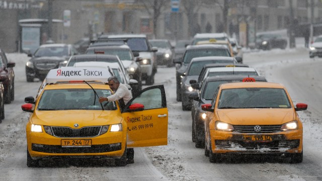 Seorang supir taksi membersihkan pembersih kaca kendaraannya di Moskow, Rusia. (Foto: REUTERS/Maxim Shemetov)