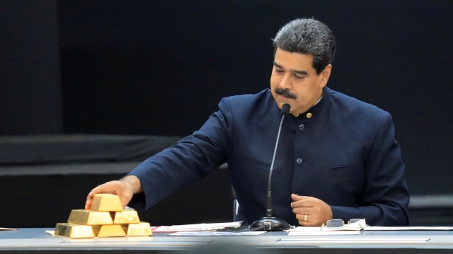 Presiden Venezuela Nicolas Maduro menyentuh emas batangan saat konferensi pers di Istana Miraflores di Caracas, Venezuela pada 22 Maret 2018. (Foto: REUTERS/Marco Bello)