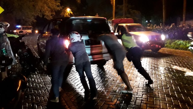 Sejumlah warga membantu mendorong mobil yang mogok akibat banjir di Kawasan Citraland, Surabaya, Kamis (31/1). (Foto: Yuana Fatwalloh/kumparan)