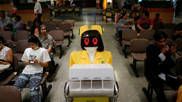 Robot yang mengenakan kostum perawat membawa dokumen medis di Rumah Sakit Umum Mongkutwattana di Bangkok, Thailand. Foto: REUTERS/Athit Perawongmetha