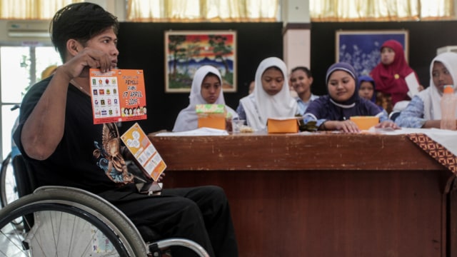 Relawan KPU Yogyakarta Basis Disabilitas, Roby Solahudin (kiri) memberikan sosialisasi Pemilu kepada penyandang disabilitas di SLB N Pembina, Giwangan, Yogyakarta. Foto: Antara/Wahyu Putro A