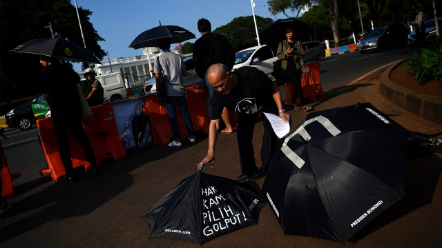 Aktivis di aksi Kamisan ke-573 menuliskan di payung hitam "Hak Kami Pilih Golput". Foto: ANTARA FOTO/Sigid Kurniawan