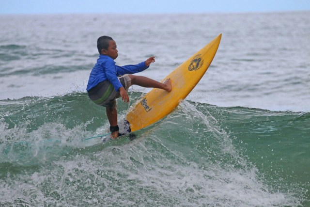 LINCAH: Galih, salah satu surfer cilik asal Kabupaten Malang turut ambil bagian dalam kompetisi surfing se Malang raya, minggu (10-2-2019) lalu. (Foto: Disparbud Kabupaten Malang For Tugumalang.id)