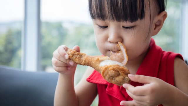 Ilustrasi anak makan ayam goreng cepat saji Foto: Shutterstock