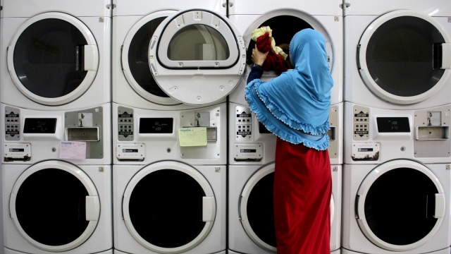 Pekerja memasukkan pakain ke dalam mesin cuci di salah satu tempat usaha penyedia jasa pencucian pakaian atau laundry di Makassar, Sulawesi Selatan, Rabu (13/2). Foto: ANTARA FOTO/Arnas Padda