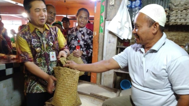 Walikota Banjarmasin Ibnu Sina (kiri) membagikan bakul purun sebagai pengganti tas plastik di pasar tradisional di Banjarmasin, Kamis (14/2/2019). Foto: Zahidi/banjarhits.id