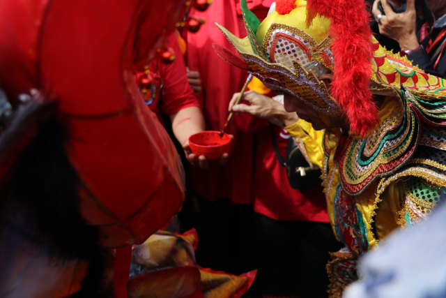 Seorang Tatung membubuhi mantra pada kepala naga yang mengikuti ritual buka mata di Vihara Tri Dharma Bumi Raya Singkawang, Minggu (17/2). Dok. Media Centre Singkawang