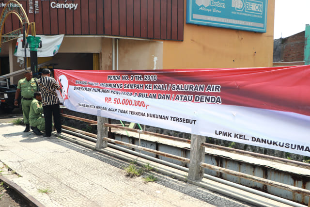  Petugas Linmas memasang spanduk larangan membuang sampah sembarangan di Sungai Jenes, Solo / Foto : Fernando Fitusia