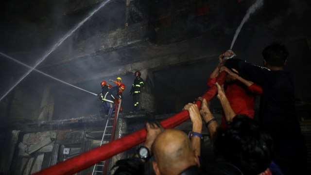 Petugas di bantu warga berusaha memadamkan kebakaran di gudang bahan kimia di Dhaka, Bangladesh. Foto: REUTERSMohammad Ponir Hossain