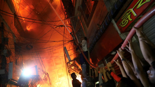 Petugas di bantu warga berusaha memadamkan kebakaran di gudang bahan kimia di Dhaka, Bangladesh. Foto: REUTERSMohammad Ponir Hossain