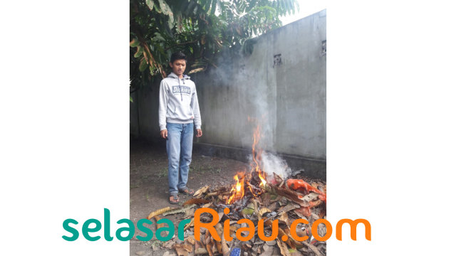 SEORANG mahasiswa UIN Suska Pekanbaru, saat membakar sampah di halaman kost tempat tinggalnya di Jalan Kamboja, Tampan, Pekanbaru. 
