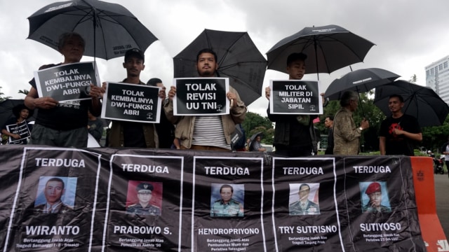 Sejumlah peserta aksi kamisan membawa payung dan baliho di seberang Istana Presiden, Kamis, (21/2). Foto: Iqbal Firdaus/kumparan