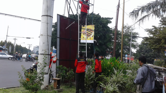 Petugas dari BPPKD Kota Solo membongkar reklame ilegal di kawasan taman kota perempatan Stadion Manahan, Solo, Senin (25/02/2019). (Agung Santoso)