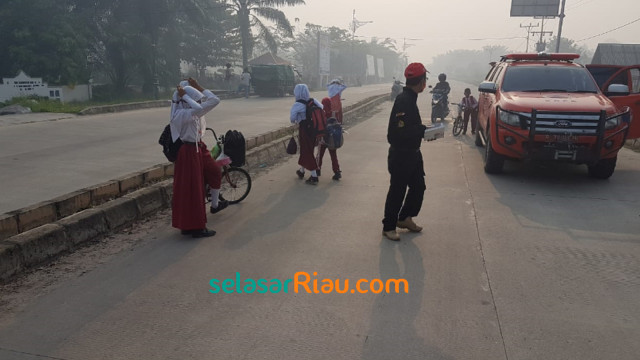 MURID-MURID SD di Pulau Rupat menerima masker pemberian BPBD Bengkalis yang diserahkan di jalan-jalan, Senin, 25 Februari 2019.  
