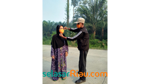 SEORANG petugas BPBD Bengkalis memasangkan masker ke wajah seorang warga di Pulau Rupat, Kabupaten Bengkalis, Senin, 25 Februari 2019. 