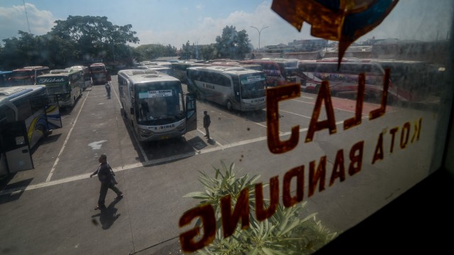 Penumpang berjalan di depan bus yang terparkir di Terminal Cicaheum, Bandung, Jawa Barat, Selasa (26/2). Foto: ANTARA FOTO/Raisan Al Farisi