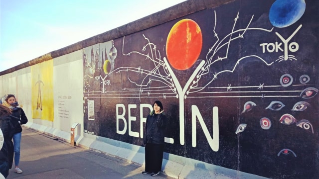 Pengunjung berfoto di tembok Berlin yang telah diubah menjadi galeri untuk mural, di Jerman. Foto: Daniel Chrisendo
