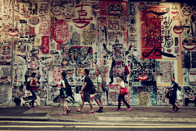 Orang-orang berjalan di depan sebuah mural di jalanan Hong Kong Foto: Shutterstock