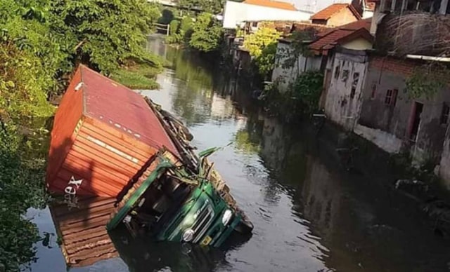 Truk trailer bermuatan tripleks nyemplung ke sungai di Ketegan, Taman, Sidoarjo (foto: Istimewa)