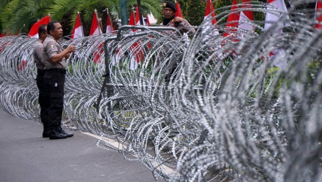 Petugas keamanan memasang ram kawat jelang aksi gabungan massa FUI dan Gerakan Jaga Indonesia di depan Kantor KPU, Jalan Imam Bonjol, Jakarta Pusat, Jumat, (1/3). Foto: Jamal Ramadhan/kumparan