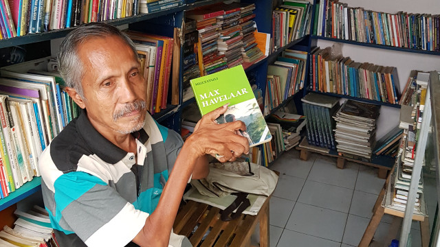 Bambang Hermanto,59, salah seorang pedagang buku yang mengalami gangguan syarah menunjukan buku Max Havelaar karya Multatuli. (foto: Irham Thoriq/Tugu Malang).